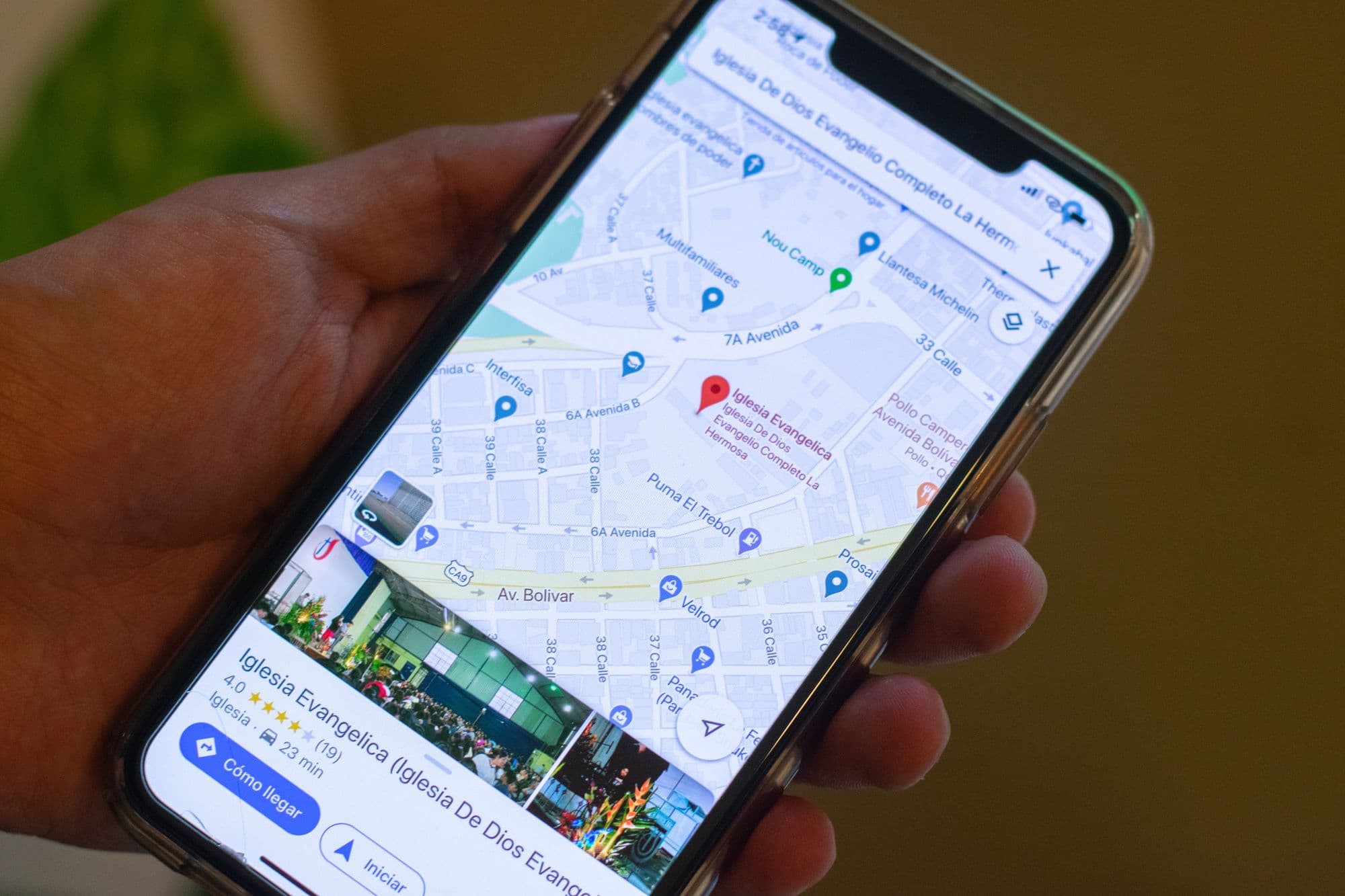 A hand holding a phone with a local business listing open in Google Maps