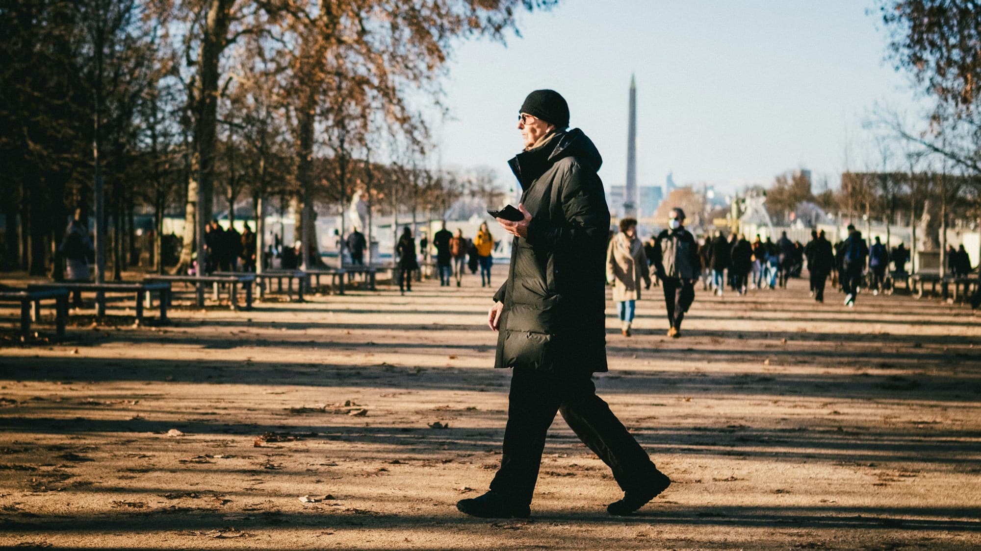 A person checking their phone while walking through a public square