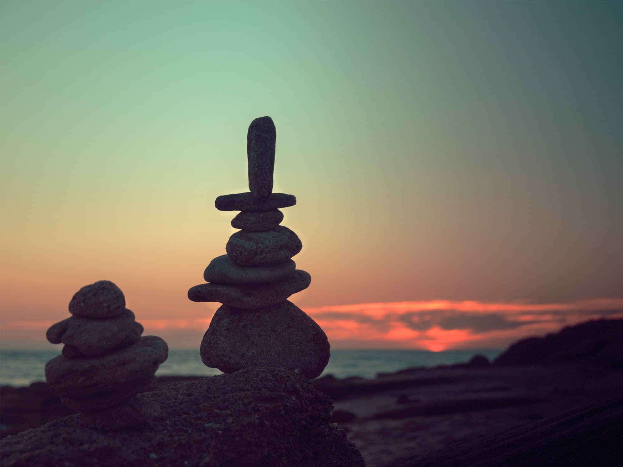 Balanced stones silhouetted against a calm sunset sky
